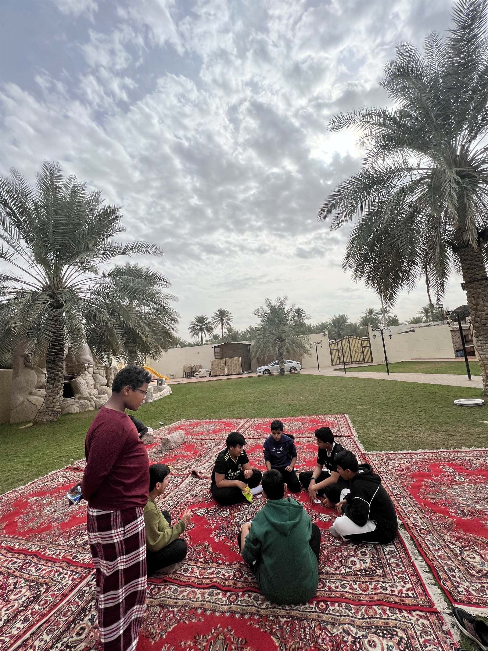 Students seated on carpets at an outdoor majlis in Al-Ahsa