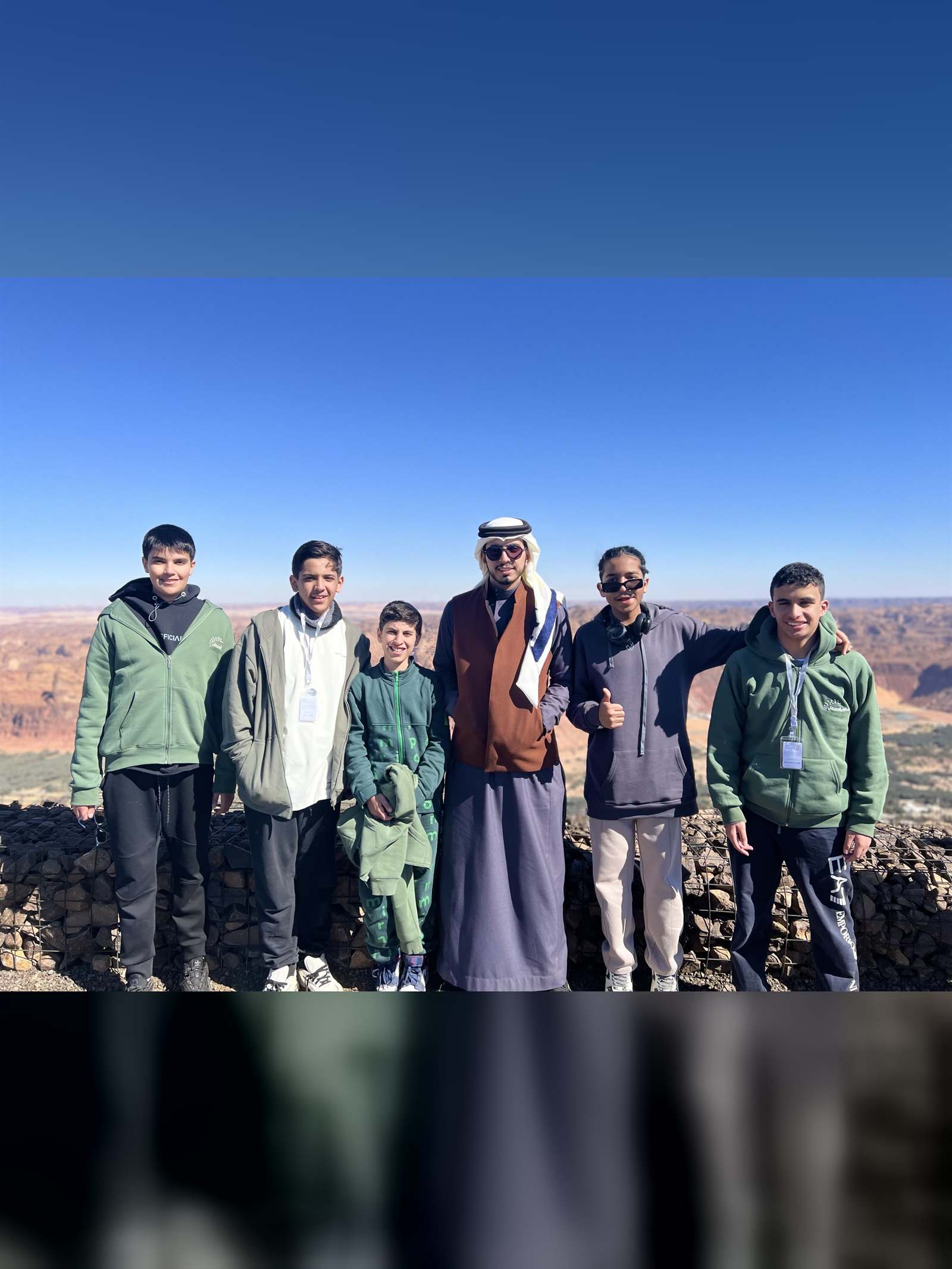 Students standing at the rim of a rock canyon in AlUla