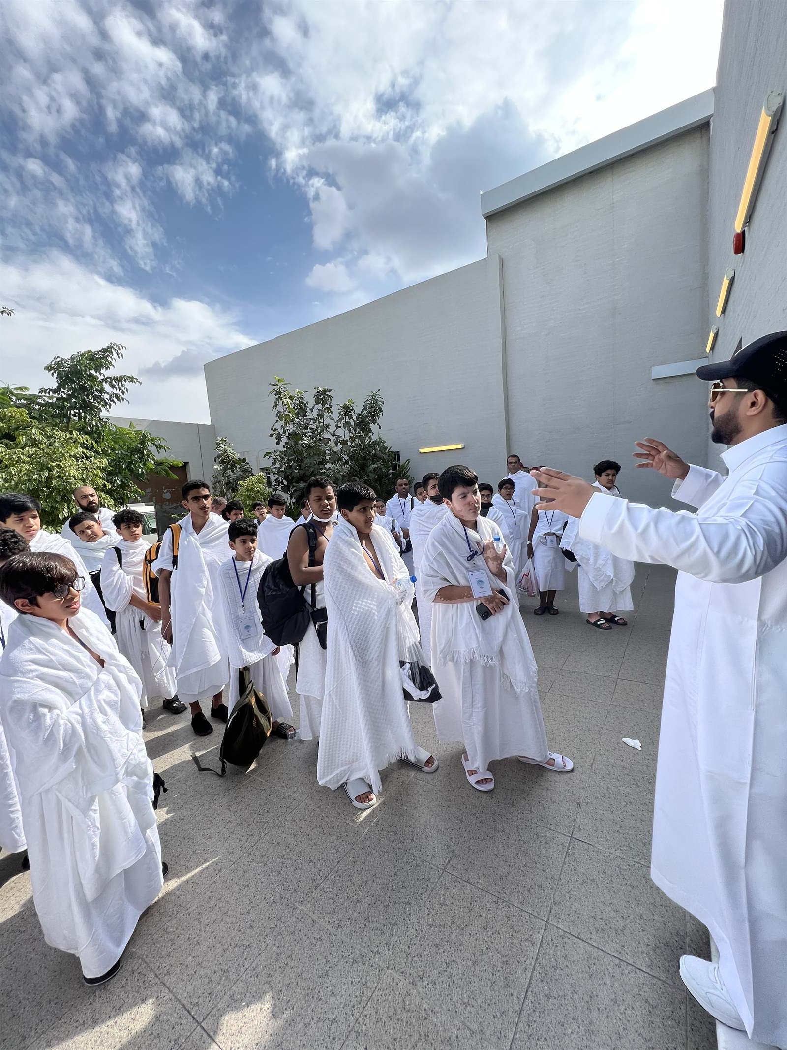A supervisor briefing a student group in ihram in Makkah
